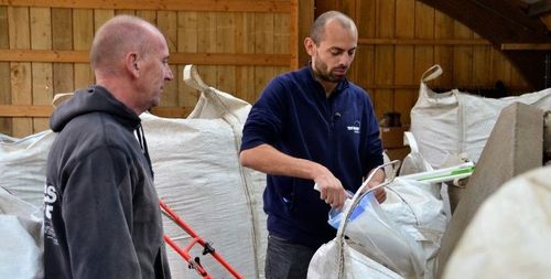 Nelis D'Hollander (r) schept ter controle een sample van het veevoeder in een zakje. Bioboer René Verachtert (l) kijkt toe.  (c) VLAM